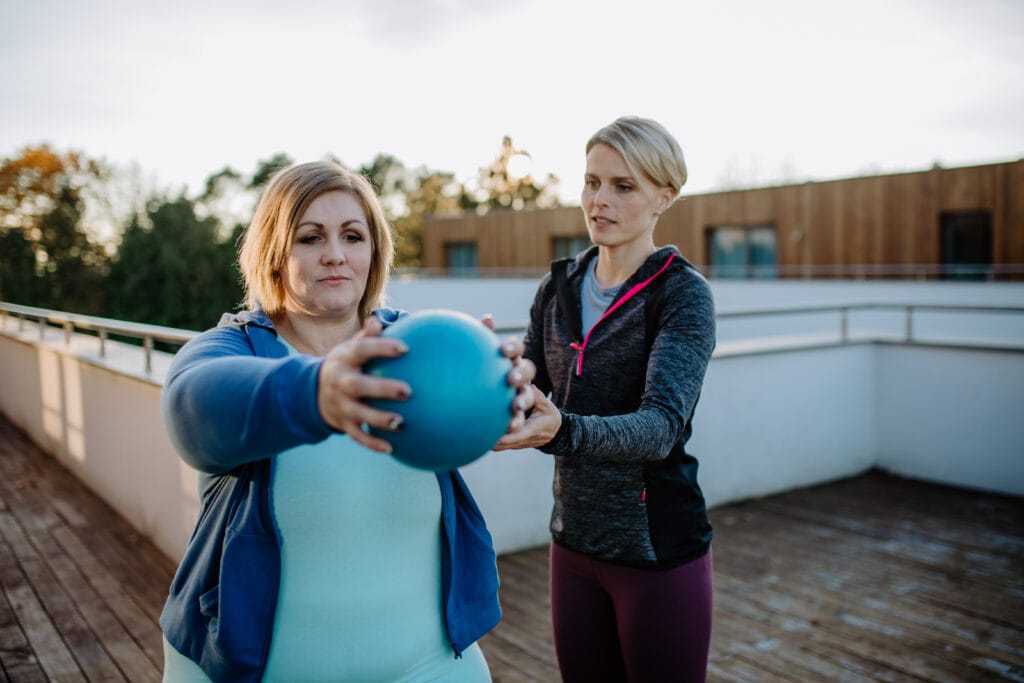 personal trainer guiding her client through a workout at home