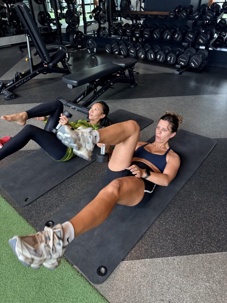 Residents doing dumbbell core exercises on mats in the community gym
