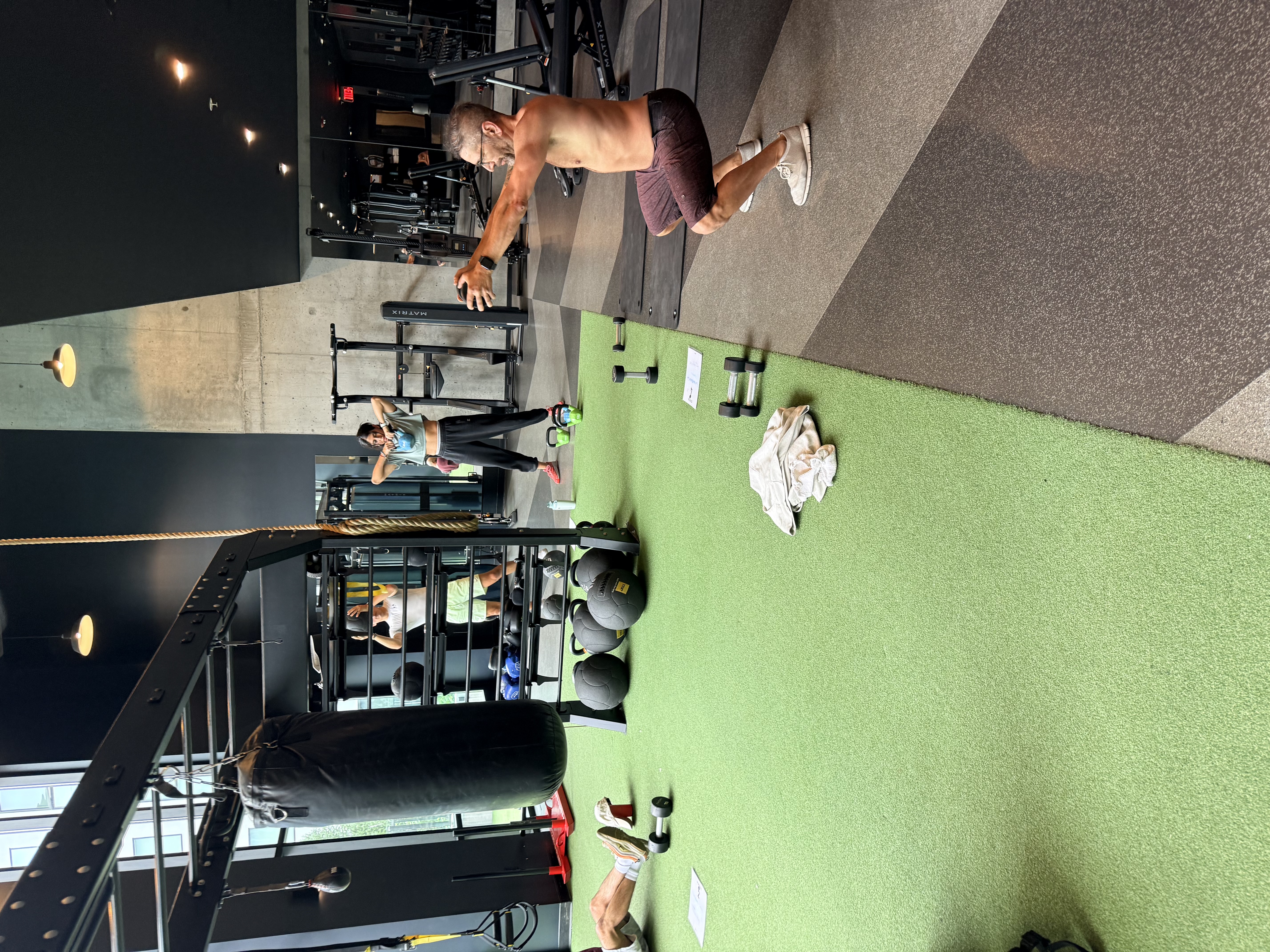 A resident squatting with a medicine ball while others train